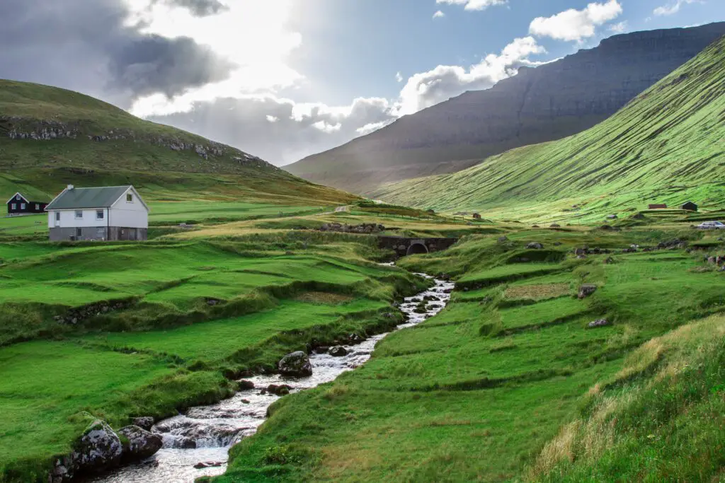 the untamed beauty of the Faroe Islands, where rugged landscapes, cascading waterfalls, and free-roaming sheep paint a masterpiece